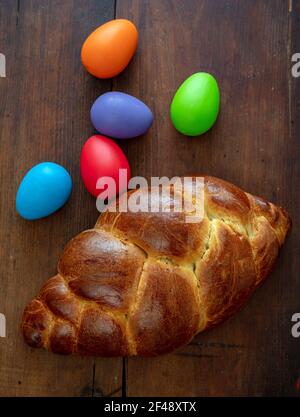 Ostereier und süßes Brot, griechischer Tsoureki cosonac Laib auf Holztisch Hintergrund, Draufsicht, Festliche traditionelle Religion Dessert, geflochtene Brioche, Stockfoto