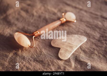 Pink Gua Sha Stein und Walze für Massage und Blume Stockfoto