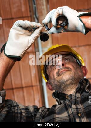 Elektriker bei der Arbeit ersetzt die Lampenfassung in einer elektrischen Wohnanlage. Bauindustrie, Energiesektor. Stockfoto