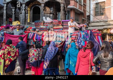 Händler im Zentrum von Kathmandu, Nepal, verkaufen Textilien und Stoffe von Tempeltreppen Stockfoto