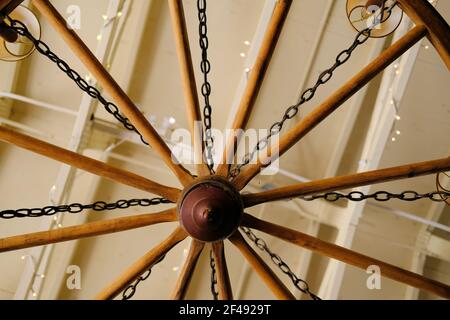 Blick von unten auf ein Waggonrad, das in eine Kronleuchter-Leuchte umgewandelt wurde; rustikales Interieur und Design. Stockfoto