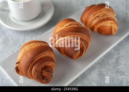 Auf einem hellen Hintergrund ein frisch gebackenes duftendes Croissant mit Eine Tasse Milch Stockfoto