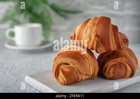 Auf einem hellen Hintergrund ein frisch gebackenes duftendes Croissant mit Eine Tasse Milch Stockfoto