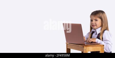 Banner, Langformat. Ein Schulmädchen sitzt mit einem Lächeln vor einem Laptop. Online-Lernkonzept. Fernunterricht während einer Pandemie. Hintergrund mit Stockfoto
