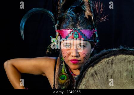 Nahaufnahme der jungen Frau Teotihuacana, Xicalanca - Toltec in schwarzem Hintergrund, mit traditionellem Kleidungstanz mit einem Trappings mit Federn und Trommel Stockfoto