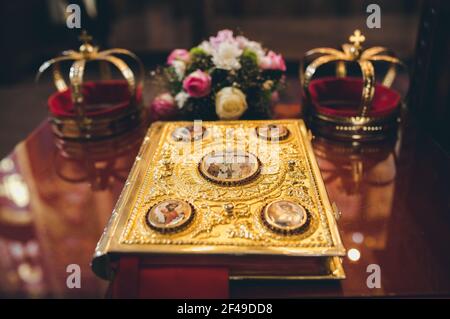 Ein Evangeliumsbuch auf dem Kirchenaltar und zwei religiöse Kronen im Hintergrund Stockfoto