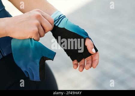Nahaufnahme der Hände der professionellen Radfahrerin Putting Auf Radhandschuhen beim Training Stockfoto