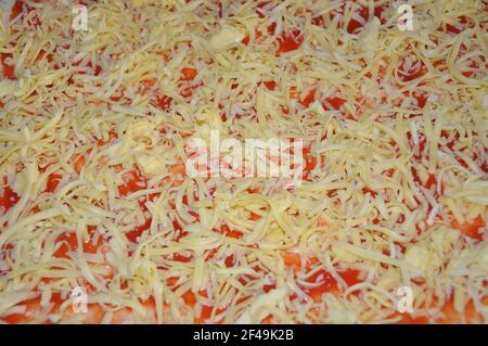 Hintergrundtextur von ungebackenen Mozzarella auf einer Pizza. Bild von ungebackene Pizza mit Schinken und Käse, Nahaufnahme Stockfoto