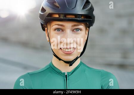 Porträt einer attraktiven jungen Frau, Radfahrerin trägt Fahrradhelm lächelnd an der Kamera, während im Freien an einem Tag posieren Stockfoto