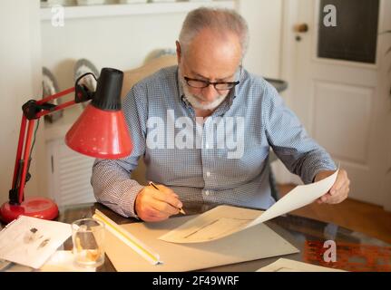 Älterer Mann unterhaltsam Zeichnung einige Pläne zu Hause Stockfoto