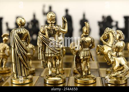 Rückseite der goldenen Königin König Centurion und Ritter Schach Stück Figuren auf Schachbrett mit Blick auf schwarz gegnerische Armee Stockfoto