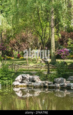 Suzhou, China - 3. Mai 2010: Bescheidener Verwaltungsgarten. Portrait der Parkecke mit Felsen, grünem Wasserteich und grünem und rotem Laub in Combinati Stockfoto