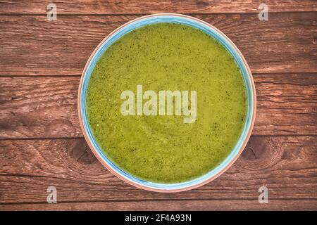 Frische Gemüsesuppe aus Erbsen in einem Teller auf braunem Holztisch, Draufsicht mit Platz für Text. Lecker Stockfoto