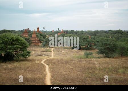 BAGAN, NYAUNG-U, MYANMAR - 2. JANUAR 2020: Eine Schotterschiene, die in der Ferne zu den historischen buddhistischen Tempeln führt Stockfoto