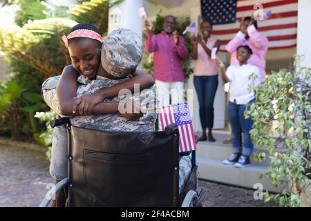 afroamerikanischer Soldat Vater im Rollstuhl umarmt Tochter drei Generation Familie dahinter Stockfoto