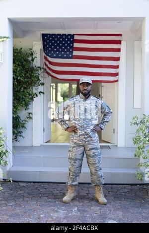 afroamerikanischer Soldat, der vor der amerikanischen Flagge steht Außerhalb des Hauses Stockfoto