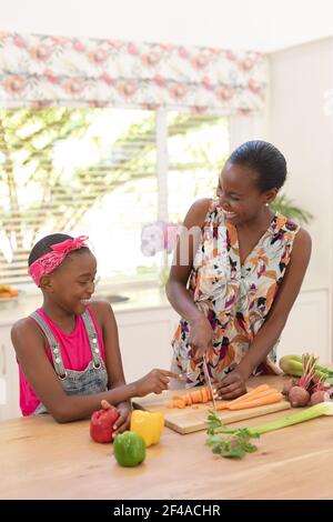 Lächelnde afroamerikanische Mutter lehrt Tochter Kochen in der Küche Stockfoto