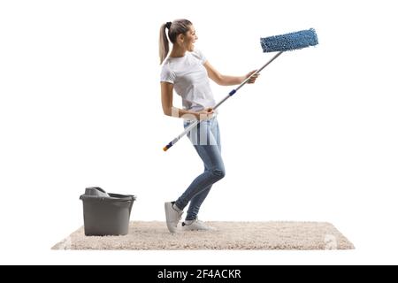 Junge Frau auf einem Teppich, die mit einem Putzmopp tanzt Isoliert auf weißem Hintergrund Stockfoto