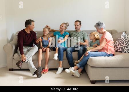Älterer kaukasischer Mann, der auf der Couch sitzt und mit seinem Lächeln spricht Familie in drei Generationen Stockfoto