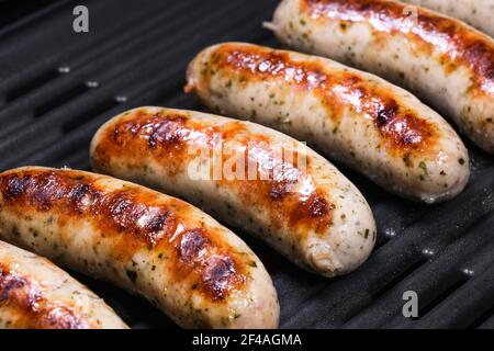 Leckere deutsche Würstchen auf dem Grill Elektrogrill. Leckere Würste sizzling auf einem tragbaren elektrischen Grillen auf einem Sommer Picknick, Nahaufnahme. 4K Stockfoto