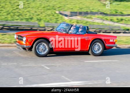 Triumph TR6 Oldtimer fahren in Southend on Sea, Essex, Großbritannien. Roter Cabrio-Oldtimer mit Top Down an einem hellen sonnigen Tag Stockfoto