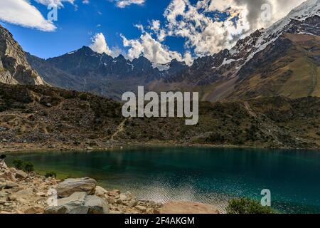 Sonniger Himmel mit schönen weißen Wolken über dem Schnee Salkantay Bergkette und Gipfel und das kalte blaue Wasser Des Humantay Sees in Peru Stockfoto