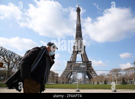 Paris, Frankreich. März 2021, 19th. Ein Mann mit Gesichtsmaske geht am 19. März 2021 im Champ de Mars in Paris, Frankreich. Der französische Premierminister Jean Castex kündigte am Donnerstag "neue massive Maßnahmen" an, um COVID-19 in den 16 am stärksten betroffenen Regionen des Landes, darunter Paris, einzudämmen. Ab Freitag Mitternacht sollen etwa 18 Millionen Franzosen in Regionen wie Paris, Hauts-de-France im Norden sowie den Alpes-Maritimes am Mittelmeer zu Hause bleiben, kündigte Castex bei einer Pressekonferenz zur Seuchenlage an. Kredit: Gao Jing/Xinhua/Alamy Live Nachrichten Stockfoto