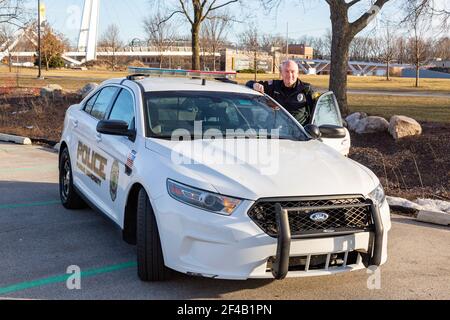 Ein Polizeibeamter der Purdue University Fort Wayne steht neben einem weißen Streifenwagen auf dem Campus. Stockfoto