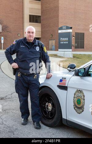 Ein Polizeibeamter der Purdue University Fort Wayne steht neben einem Streifenwagen auf dem Campus. Stockfoto