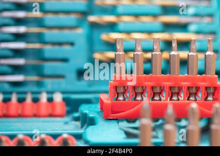 Bohrer-Kit, Nahaufnahme. Hintergrundstruktur der Hardware. Blaues Set mit einer Variante roter Bohrersätze und Schraubendreher. Defokussierte und abstrakte Sorten von Stockfoto