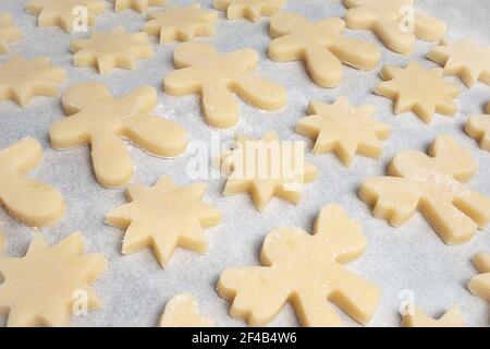 Viele Kekse auf Backblech. Diagonale Reihen von kurzen Brot Cookies Teig in verschiedenen Formen wie: Stern, Lebkuchen Mann und Engel. Herkömmlicher Chr Stockfoto