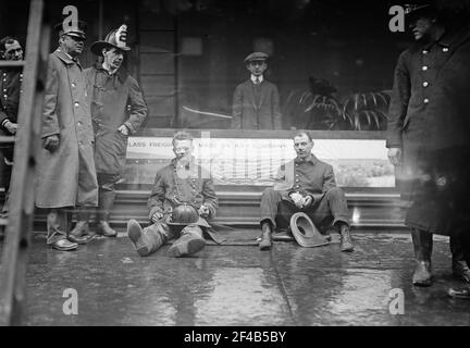 Feuerwehrleute saßen auf dem Bürgersteig, nachdem sie einen Brand in einem U-Bahn-Tunnel in New York City bekämpft hatten, der in der Nähe der West 55th Street und des Broadway am 6. Januar 1915 stattfand Stockfoto