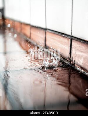 Wassertropfen spritzt in Bewegung. Regentropfen fallen auf Ziegelsteine in der Ecke. Konzept für Wasserlecks oder defekte oder verstopfte Regenleitungen. Abstract und d Stockfoto