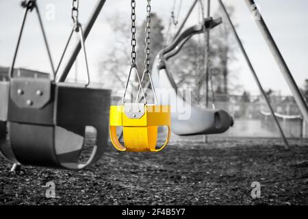 Spielplatz Schaukel Set für Kleinkinder mit vollen Eimer Sitze, Nahaufnahme. Schwarz-weißes Bild mit einem Sitz in hellgelber Akzentfarbe. Selektive Farbe Stockfoto