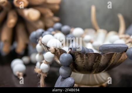 Holzperlen Dekoration auf dem Tisch, Nahaufnahme. Blaue und weiße Perlen drapiert über Gericht. Weiche, gedämpfte braune, grüne und blaue Farben. Dekoration im Hintergrund. Auswahl Stockfoto