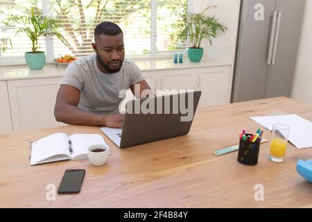 afroamerikanischer Mann, der mit einem Laptop am Schreibtisch sitzt Zu Hause Stockfoto
