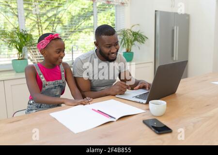 afroamerikanische Vater und Tochter sitzen mit Laptop arbeiten aus Zu Hause Stockfoto