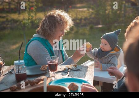 Frau mit kleinem Kind sitzt an einem Holztisch in Der Garten Ostern Stockfoto