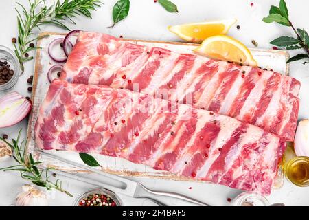 Frische rohe Schweinefleischrippen gewürzt mit Gewürzen auf hellgrauem Hintergrund. Draufsicht Stockfoto