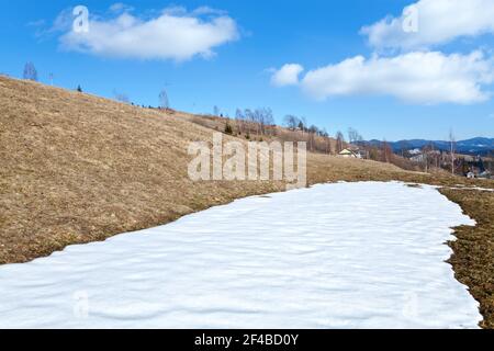 Letzter Schnee auf der Bergwiese bei einem Dorf. Ukraine, Karpaten. Stockfoto