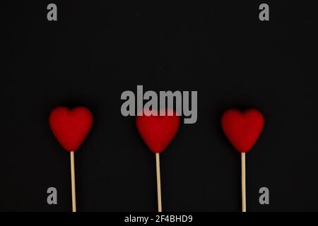 Flauschige rote Herzen, auf einem Holzstab auf schwarzem Hintergrund. Valentinstag und Liebe Konzept. Stockfoto