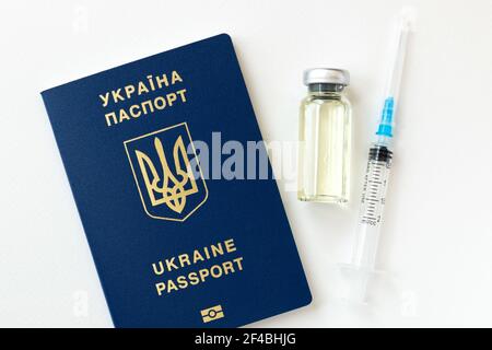 Nahaufnahme einer Coronavirus-Impfstoffflasche und einer Spritze mit blauem Ukraine-Pass auf weißem Hintergrund. Stockfoto