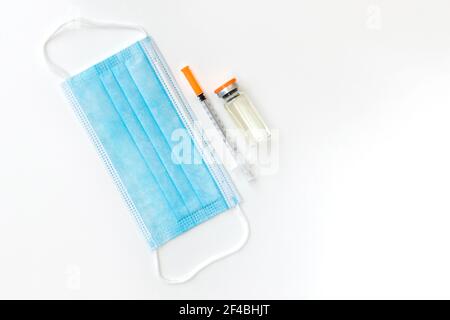 Impfstofffläschchen, Spritzen und OP-Maske isoliert auf weißem Hintergrund, flach liegend mit Platz für Text. Coronavirus-Impfstoff-Konzept. Impfung und Immu Stockfoto