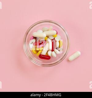 Mehrfarbige Pillen und Kapseln, Tabletten gegen das Virus, Grippe, Krankheit auf rosa Hintergrund. Medizinisches Konzept des Virus-Pandemieschutzes, Coronaviru Stockfoto