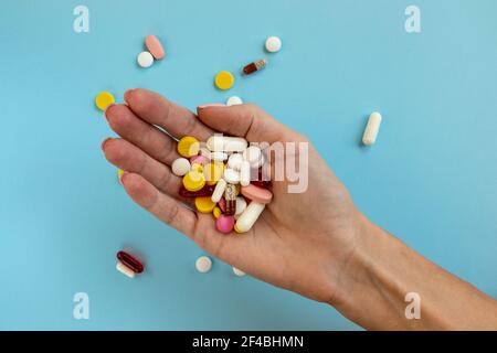 Frau hält in der Hand verschiedene medizinische Pille auf hellblauem Hintergrund. Draufsicht. Medizinkonzept. Pharmazie. Stockfoto