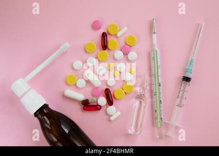 Glasflasche mit Medikamenten. Thermometer, Spritze und Pille zur Behandlung von Erkältungen auf rosa Hintergrund. Kalte Heilmittel. Medizinische Konzepte und Medikamente. Top Vie Stockfoto