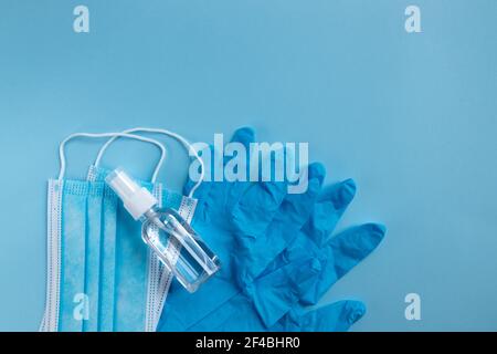 Medizinische Maske, Schutzhandschuhe und Handdesinfektionsmittel auf blauem Hintergrund. Pandemie des Coronavirus. Stockfoto