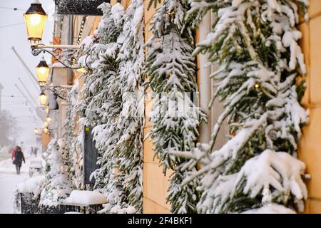 Aleksanterinkatu Straße während des starken Schneesturms. Fenster mit schneebedeckten Fichtenzweigen. Die schöne weihnachtliche Atmosphäre in Helsin Stockfoto