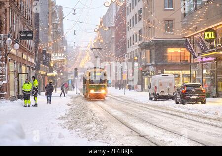 Helsinki, Finnland - 12. Januar 2021: Aleksanterinkatu Straße während des starken Schneesturms. Die Straßenbahn fährt auf der Straße. Stockfoto