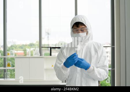 Epidemiologische Forscher in Virusschutzkleidung sorgfältig auf chemische in Glasflasche. Coronavirus-Krankheit 2019 Testverfahren in einem Stockfoto
